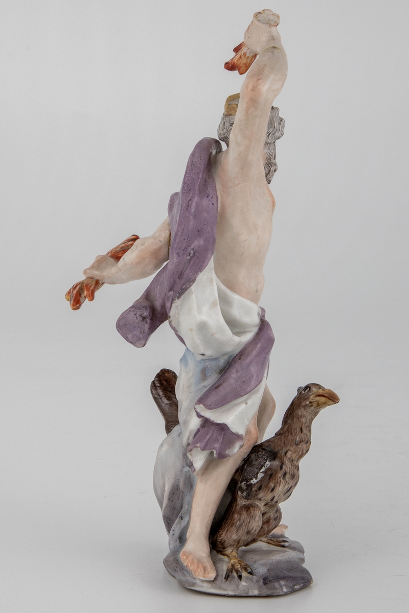 Figur av skjegget mann med ørn og tordenkiler i hendene, som skal forestille Jupiter/Zevs. Hvitglasert porselen med polykrom overglasurmaling. Han er iført et hvitt og lilla draperi, mens på hodet har han en tagget krone. Armene er hevet og han er fremstilt i det pregnante øyeblikk før han skal kaste tordenkilene.
