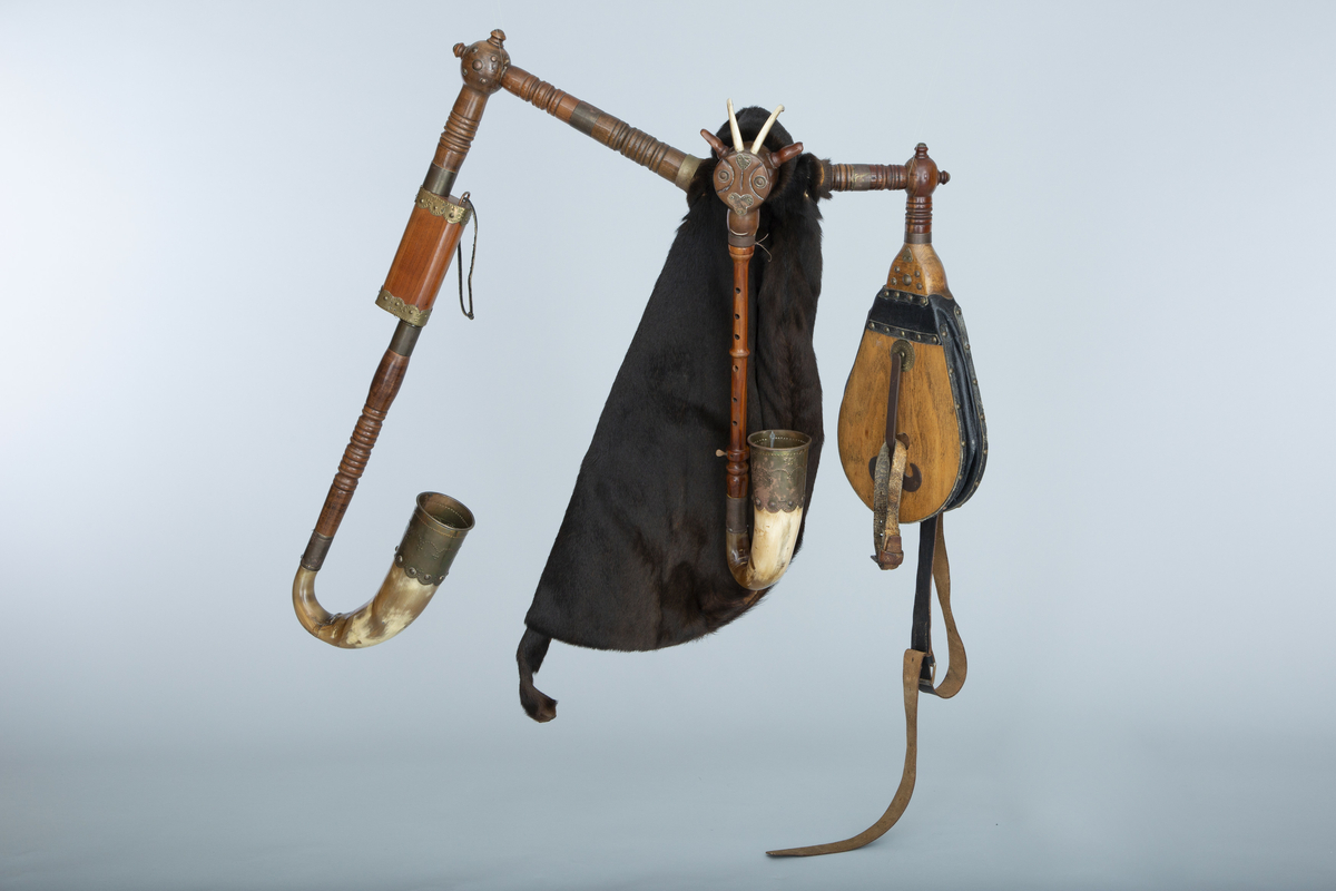 Instrument med sekk av hundeskinn, korthåret, mørk brun pels. Blåsebelg, en bordun og en melodipipe. Melodipipens øvre ende stikker ut av et skåret, stilisert bukkehode av tre med messingdekor. 6+1 fingerhull. Begge pipene har sylindrisk boring og ender i oppoverbøyde horn forsynt med hamrede messingplater. Bordunpipen består av fire dreide ledd (+horn) med messingknapper og ornamenter.