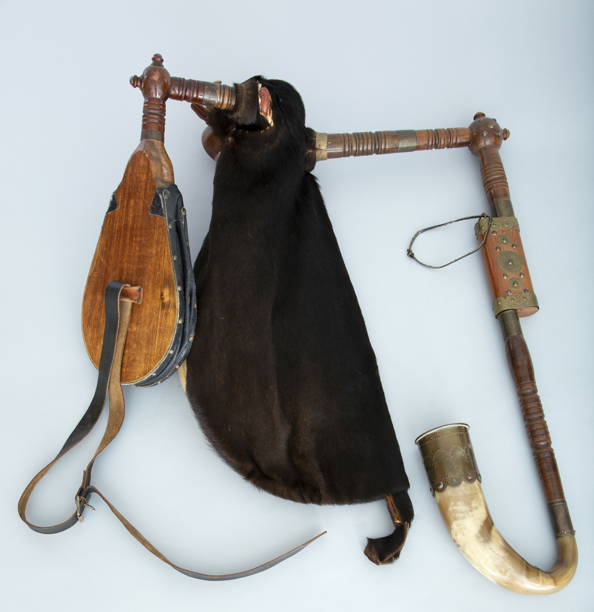 Instrument med sekk av hundeskinn, korthåret, mørk brun pels. Blåsebelg, en bordun og en melodipipe. Melodipipens øvre ende stikker ut av et skåret, stilisert bukkehode av tre med messingdekor. 6+1 fingerhull. Begge pipene har sylindrisk boring og ender i oppoverbøyde horn forsynt med hamrede messingplater. Bordunpipen består av fire dreide ledd (+horn) med messingknapper og ornamenter.