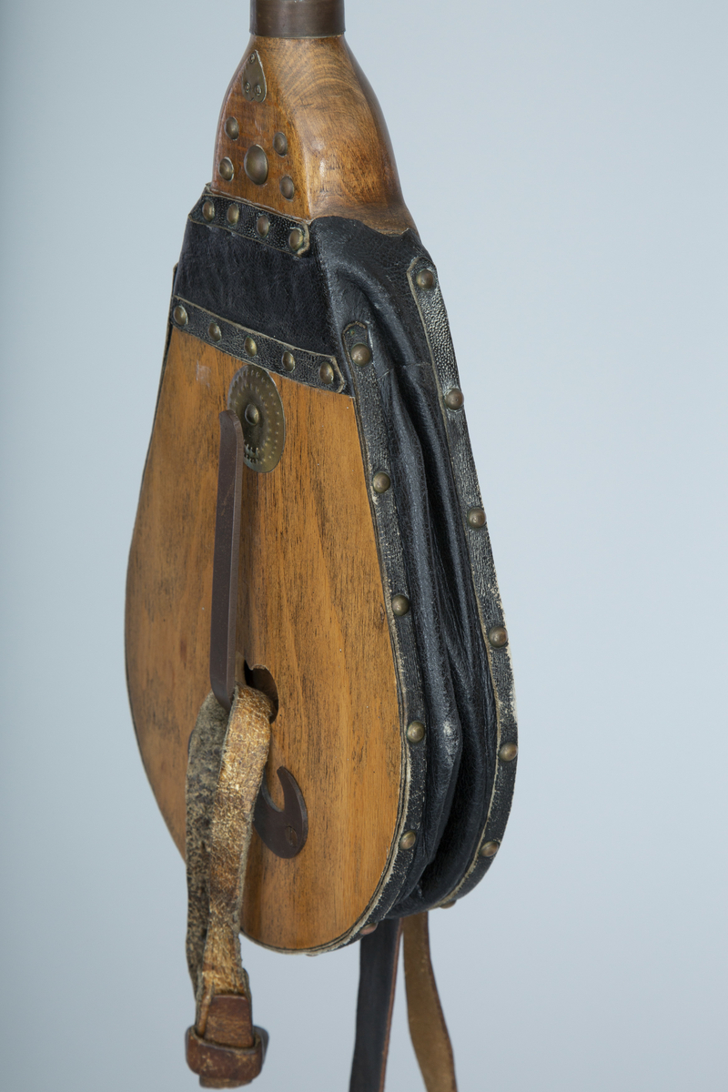 Instrument med sekk av hundeskinn, korthåret, mørk brun pels. Blåsebelg, en bordun og en melodipipe. Melodipipens øvre ende stikker ut av et skåret, stilisert bukkehode av tre med messingdekor. 6+1 fingerhull. Begge pipene har sylindrisk boring og ender i oppoverbøyde horn forsynt med hamrede messingplater. Bordunpipen består av fire dreide ledd (+horn) med messingknapper og ornamenter.