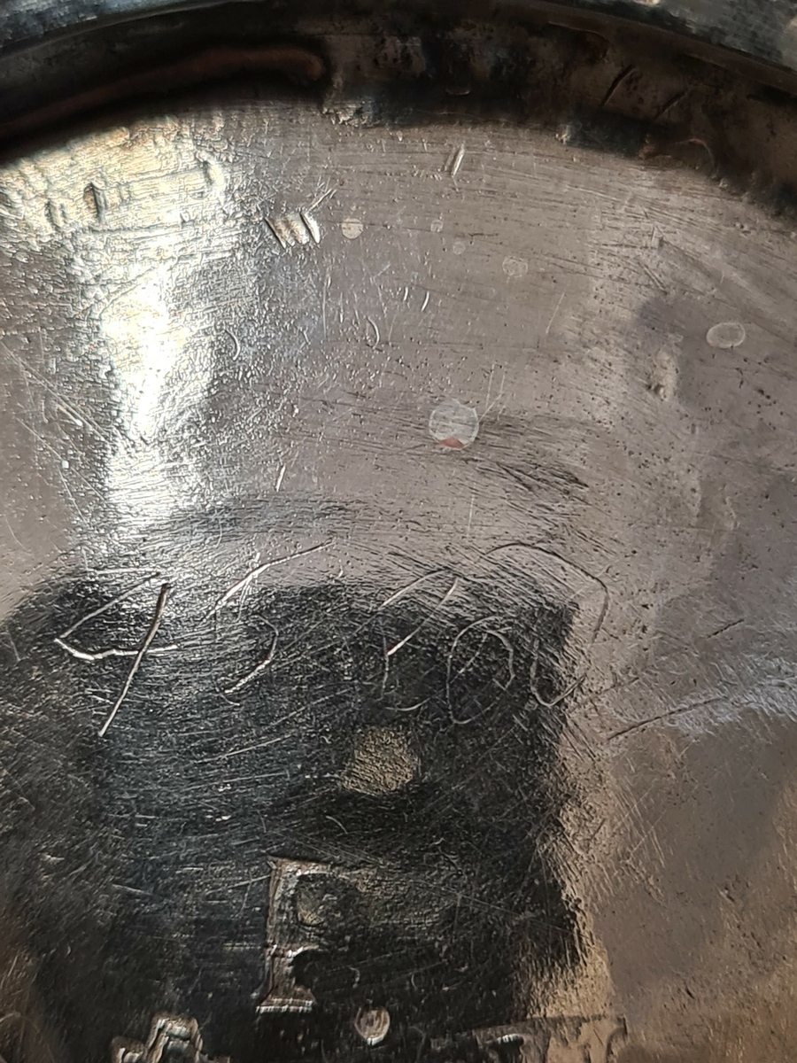 Konisk, delvis förgylld bägare stående på godronnerad fotring. Lätt utsvängd mynningskant med enkel inpunsad dekor. Bägarens övre del, under mynningskanten, är prydd runt om med en ingraverad acantusbård. Framtill finns en ingraverad kartusch med acantusslingor blandat med hantverksredskap. Bland redskapen syns en murslev, en lodlina, en spade samt en ritning på en större byggnad. Ramen är krönt av en friherrlig krona. Inom ramen finns initialerna ''HLS'' samt ''EAD''. Dessa initialer är enkelt och senare påförda. På bägarens undersida finns, förutom stämplarna, enkelt inristat, ''ESS'', ''46 lod'' samt ''45 lod''.

Johan Grönwall föddes i Växjö omkring år 1720 där han 1734 kom i lära hos A.J. Limnell. År 1743 blev han gesäll och 1753 vann han burskap som mästare i Vänersborg. Han avled i Vänersborg 1784.

Se katalog Bukowski nr. 408. Auktion 31 okt-3 nov 1978. sid. 151.