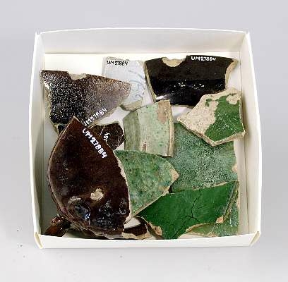 Delar av kärl. 10 stycken keramikfragment. Fyra brunglaserade bitar till mindre kärl, fem bitar grönglaserat lergods samt en vitglaserad bit med blå dekor.