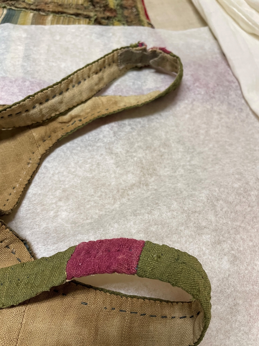 Till kvinnodräkt av brunt halvsiden med mönster i grönt och blått.