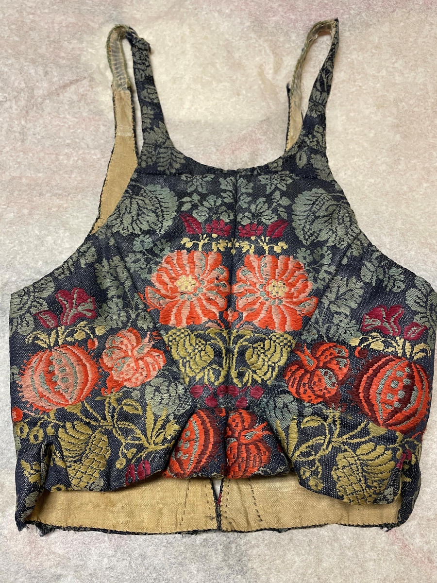 Till kvinnodräkt; brokad, grå-grön.