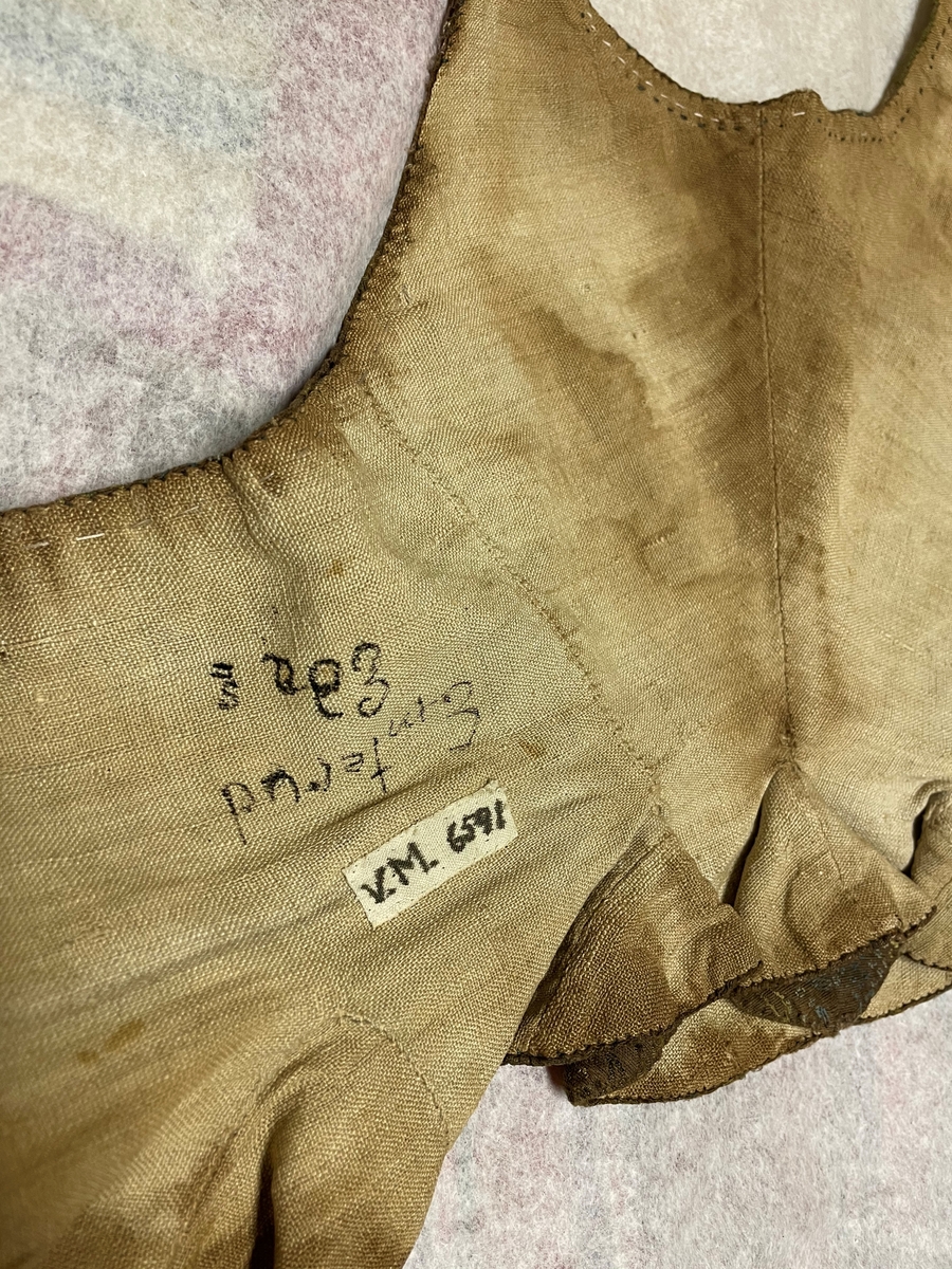 Till kvinnodräkt av brunt halvsiden med mönster i grönt och blått.