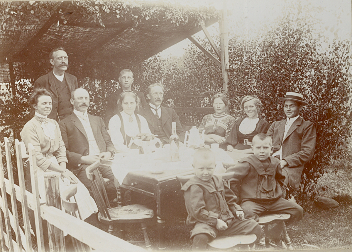 Familieselskap i lysthuset på Krossvegen i Bø.  F.v Anna Sagen, sarpsborg, Hans Sisjord ståande, Halvor H. Sagen f. 1874 d. 1955, Sarpsborg, Kari O. Saga f. 1889 d.1976, Olav H. Saga f. 1876 d. 1963, Johannes Saga ståande bak, f. 1897 d. 1981, Mari H. Saga f. 1882 d. 1973, Ronnaug Saga f. 1888 d. 1976, Kittil H. Sagen. Sitjande framme f. v Erik K. Sagen f. 1907 og Håkon K. Sagen f. 1905, begge Sarpsborg.