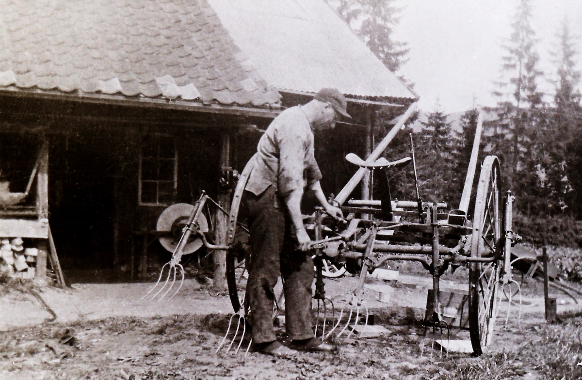 Kristian Surlien (Surlismeden) (1886-1965) i arbeid utenfor smia på Haugneshagan. Arbeider med en høyvender.