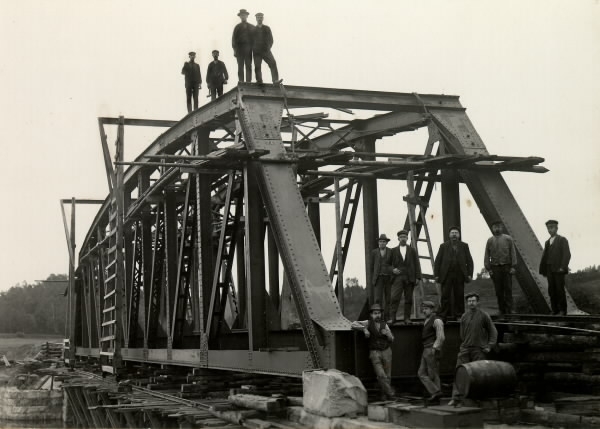 Brobygge över Ätran strax intill Ätrans station ca 1910 (anläggandet av Varberg-Ätrans järnväg pågick 1908-1911). Ett dussin rallare och arbetare från Borås. På rälsen står den s k "pinnapågen" och i förgrunden ligger en tunna.