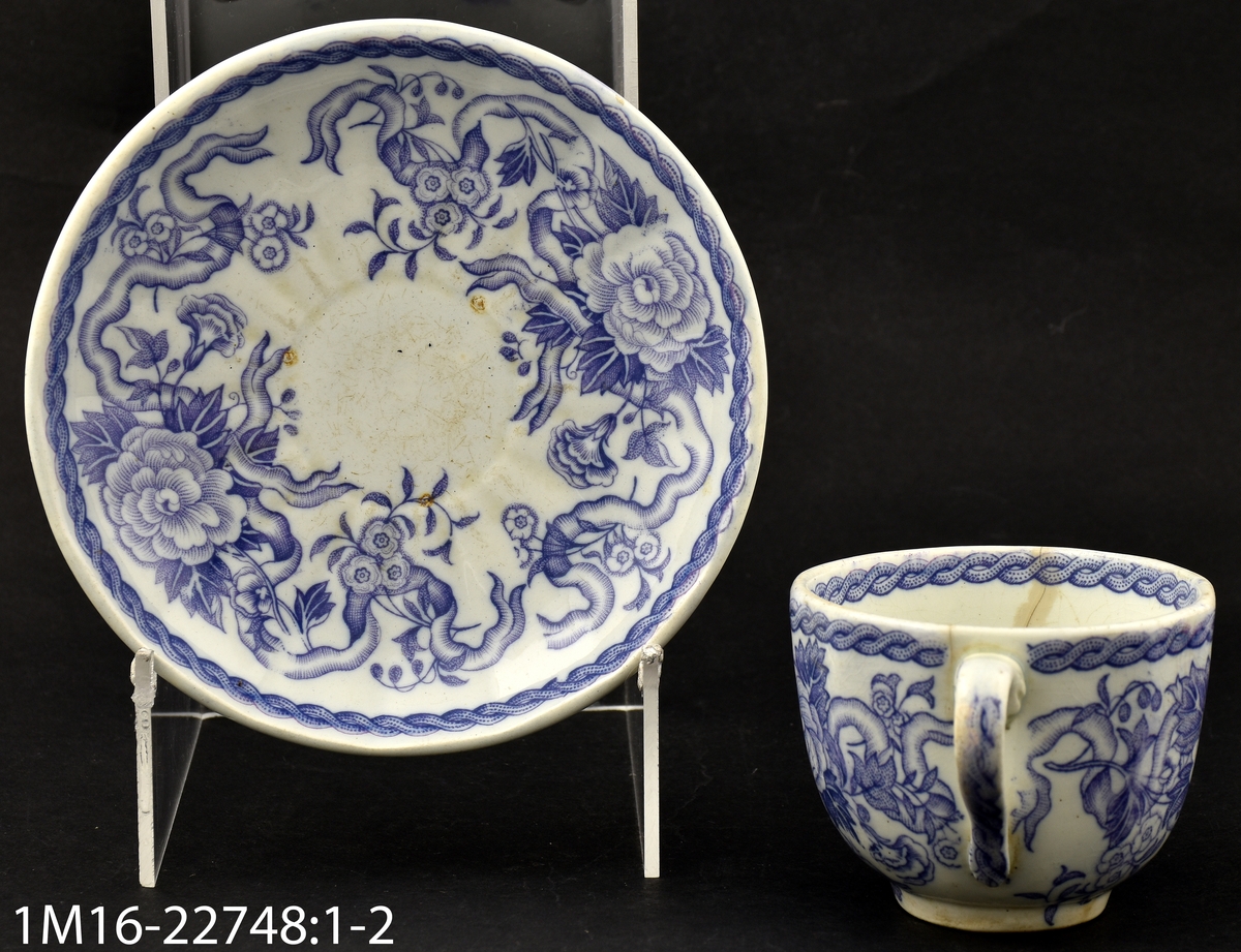 Kaffekopp med stora blommor i ljus lila, i botten av koppen IX (eller XI), i botten av fatet Lilas  (dekornamnet) inom blomkrans, inpressat Rörstrand. Ironstone.