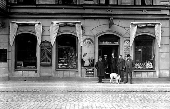 Fasad av byggnad; skylt med text "A:B WILH. BÄCKMAN FÄRGHANDEL". I förgrunden står fem män. 
Firman startades 1893 av direktör Wilh. Bäckman som en mindre färghandel. Dess första lokaler låg vid Östra Torggatan. Firman hade därefter lokaler i Hotell Grands fastighet, och efter 10 års verksamhet flyttade företaget in i en egen fastighet. De första åren omfattade  verksamheten försäljning endast av färger och oljor, men efterhand upptogs även andra artiklar. Största intresset ägnades dock åt detaljhandeln. År 1924 ombildades firman till aktiebolag med Wilh. Bäckman som verkställande direktör. Efter hans död blev Adolf Edenholm, som varit anställd sedan 1901, chef för verksamheten.
Källa: Nyblom-Svanqvist, Näringsliv i Värmland, 1945.