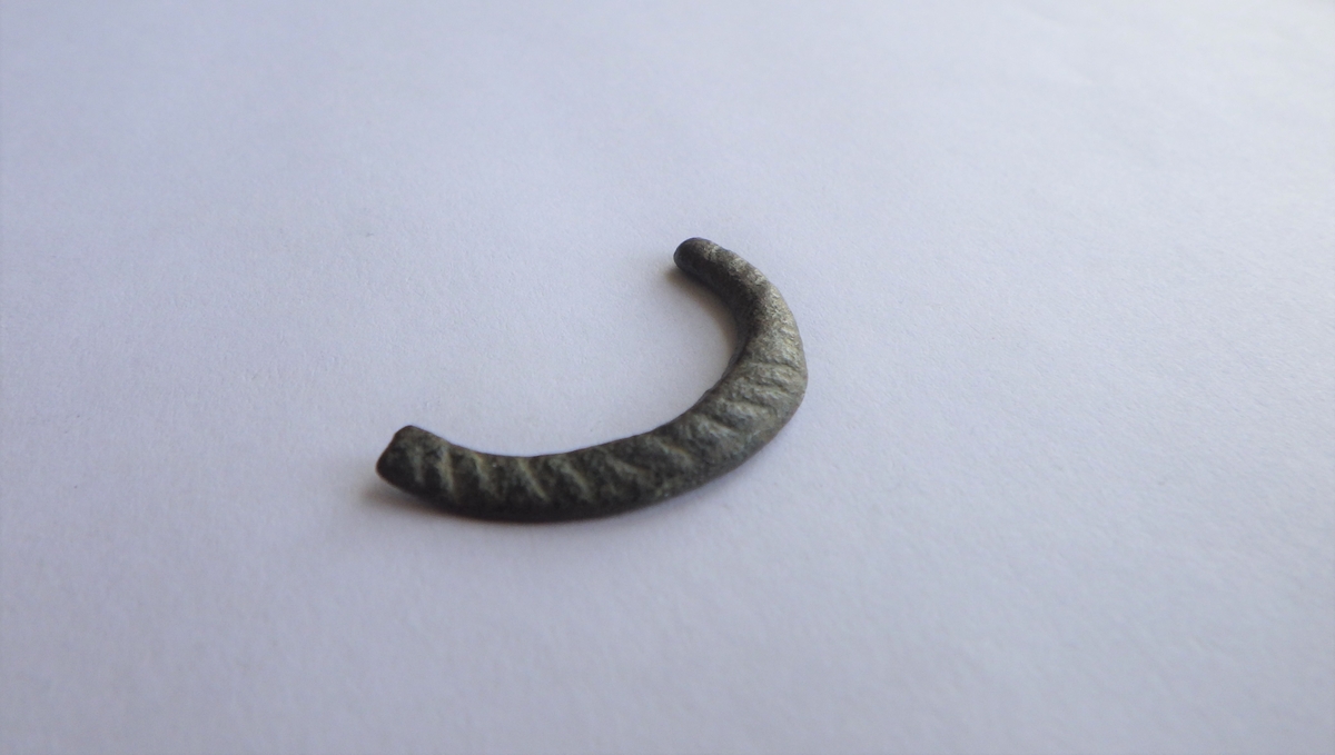 MALV: DIAM. 27, 5  T. 4, 1 MM, FRAGMENTET ER LAGET AV FLATT 4, 1 MM BREDT BÅND. DENENE SIDEN HAR RIFLE-DEKOR. TORNEN MANGLER. 