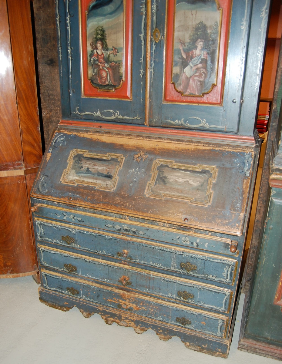 Skatoll av tre. Skapet har blå grunnfarge, og hvit og mørkeblå barokkmaling. På nederste del er det tre skuffer, med parvise håndtak laget av kobberlegering med gjennombrutt dekor. På øverste del av skapet er det to skapdører med fyllinger. I fyllingene er det malt dekor med motiv av to mennesker med blomster og fugl i hendene. Skapet har konveks koll, med to lister med gullbelagte kanter som ender i to volutter på midten. Mellom voluttene er det en gullbelagt kule med dekorative tverrsnitt. På den nedfellbare platen er det to fyllinger med profilerte lister, og malt dekor av landskapsmotiv.