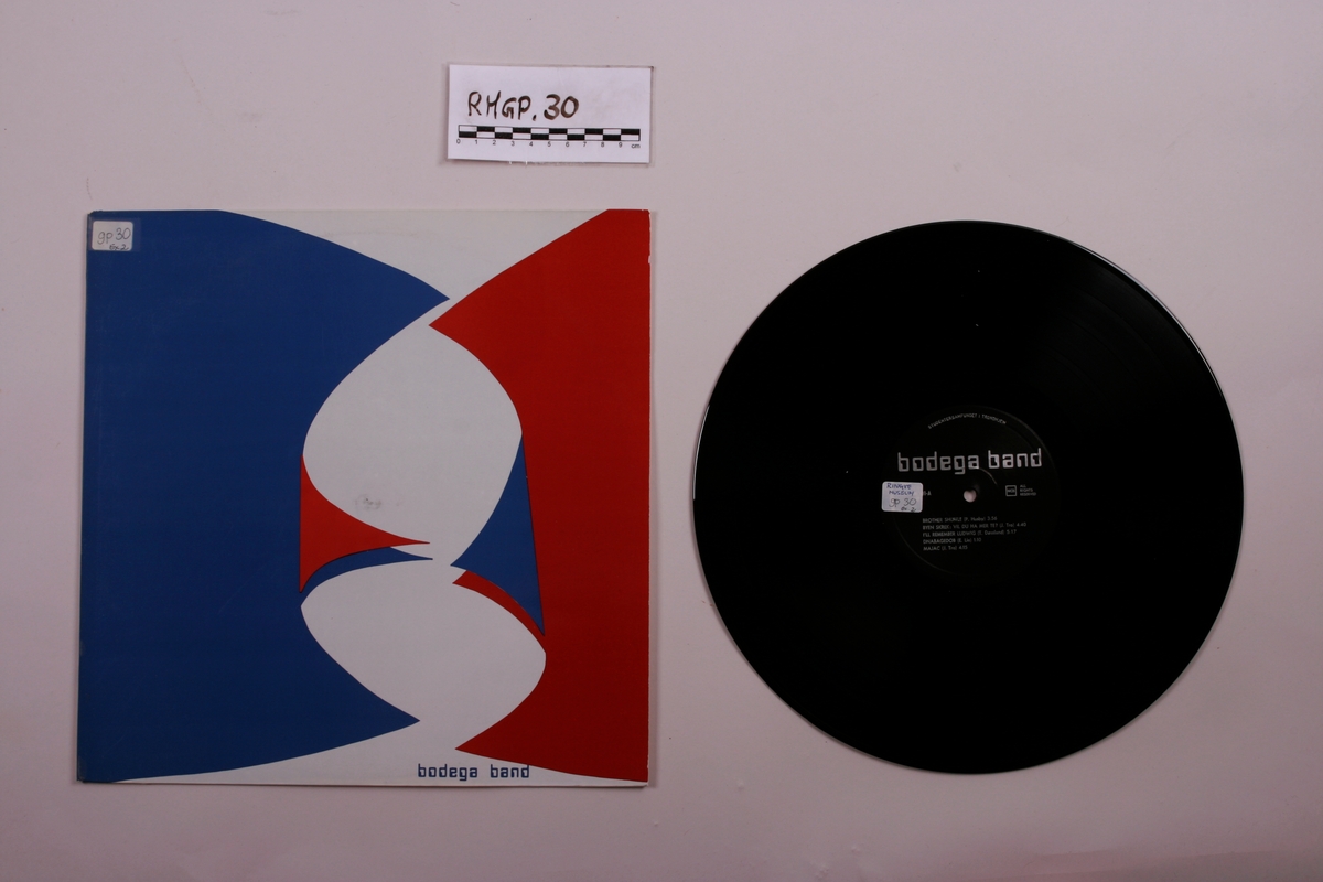 Grammofonplate i svart vinyl og plateomslag i papp. Plata ligger i en papirlomme.
