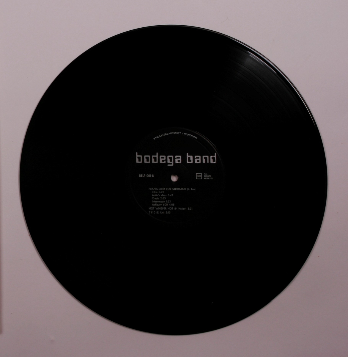 Grammofonplate i svart vinyl og plateomslag i papp. Plata ligger i en papirlomme.
