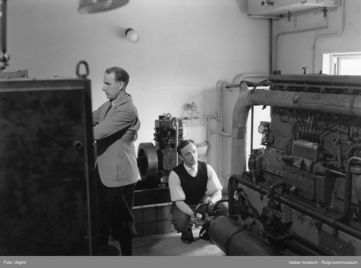 NRK-bygget i Vadsø. 2 menn i et rom med maskinelt utstyr. 
Finnmark kringkaster (NRK-bygget) i Vadsø, byggeår 1949. Arkitekt Henrik L. Kjær. Bygget har bærende betongvegger og fasadene er lagt med teglstein og grunnmuren er belagt med skiferplater. (Kilde: Arkitekturguide for Nord-Norge og Svalbard og "Fra djevelmaster til Hallo fiskeflåten" av Bård Gudmund Hansen)
Kil