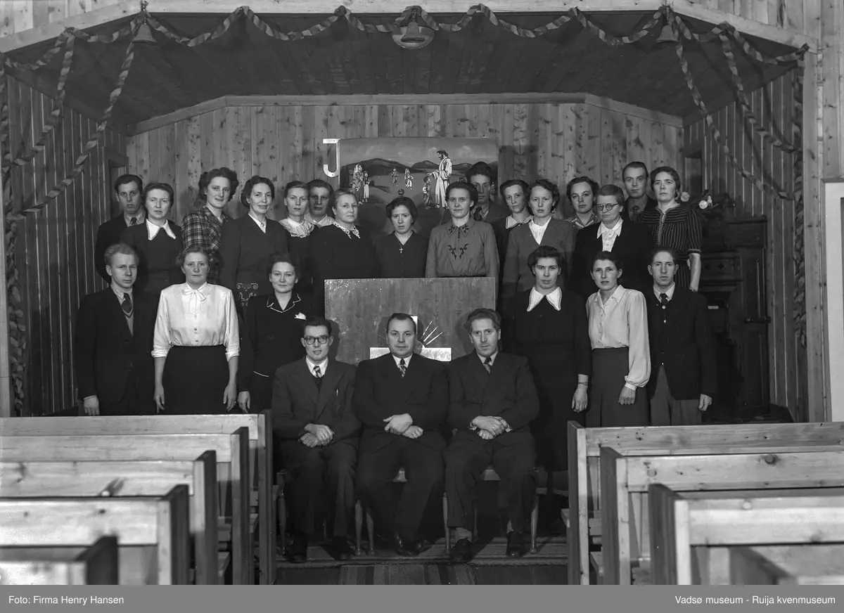 Filadelfia, Vadsø 1951. Medlemmer av Filadelfia i Vadsø. Bedehuset Filadelfia ble bygd i 1948. Bildet er tatt inne i bedehuset, hvor medlemmer av menigheten er samlet rundt prekestolen.