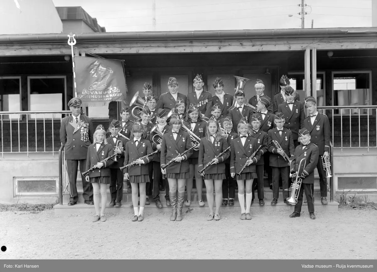 Vardø guttemusikkorps ved inngangen på Sentrum skole i Vadsø 30.juni 1969. På bildet er det både gutter og jenter blant korpsmedlemmene. 