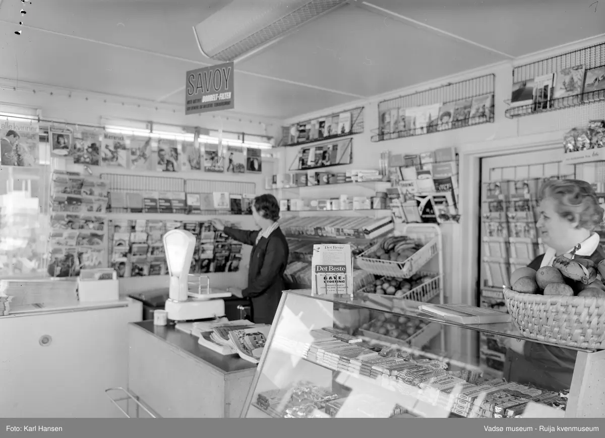 Narvesen kiosk, Vadsø 13.mai 1965. Deler av interiøret og vareutvalget i kiosken. Kioskansatte Pauline (Bølla) Stock og Anny Iversen.