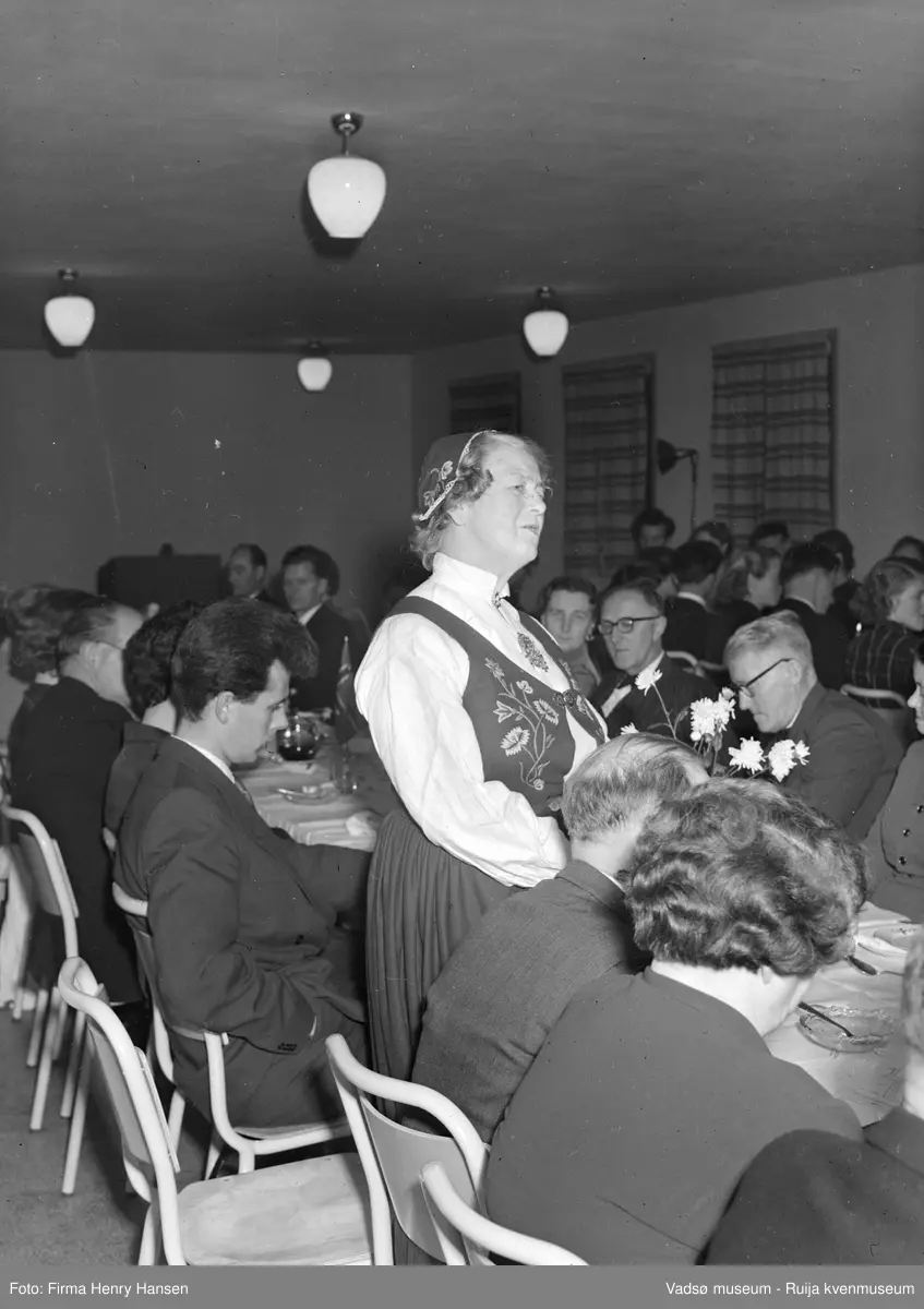 Kvinne, ukjent, holder tale på festmiddag. Bildet er trolig tatt ved innvielsesfesten for Vadsø folke- og framhaldsskole 28.10.1956. Kilde: Melding om Vadsø folke- og framhaldsskole for skoleårene 1951/52-1959/1960. Vadsø 1962.