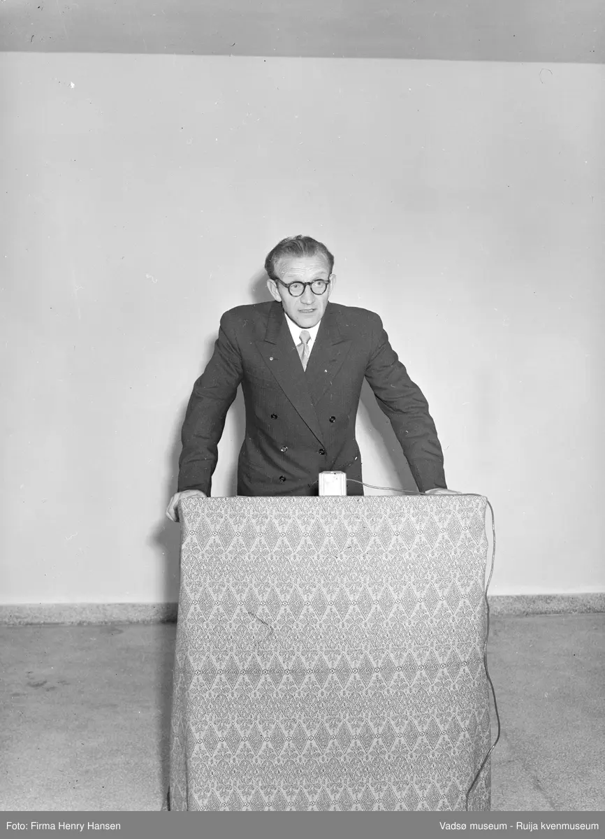 Mann, ukjent, holder tale. Bildet er trolig tatt ved innvielsesfesten for Vadsø folke- og framhaldsskole 28.10.1956. Kilde: Melding om Vadsø folke- og framhaldsskole for skoleårene 1951/52-1959/1960. Vadsø 1962.