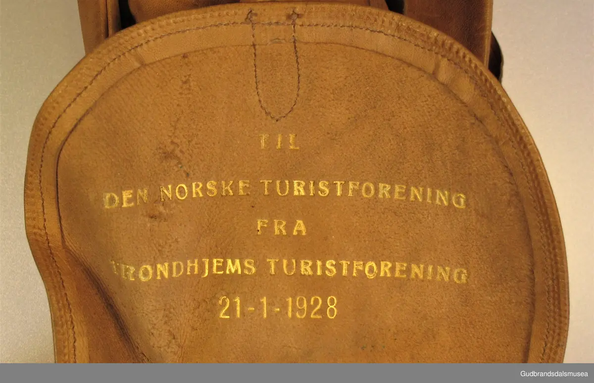 Adresse til DNT fra Trondhjems Turistforening i anledning av 60-års jubileet i 1928. Adressen er oppbevart i  LÆRHYLSE utformet som en lien ryggsekk med lokk og ryggreimer.