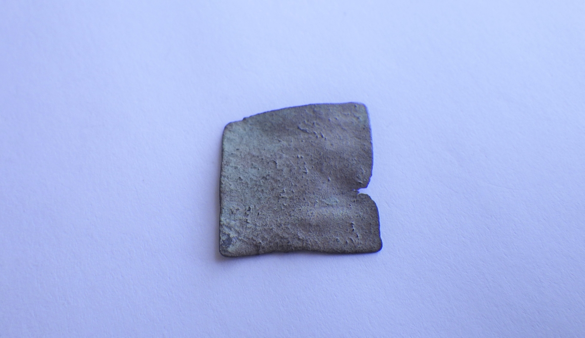 En del av en tynn , bulkete metallplate. Trolig et metallavklipp fra metallarbeid.