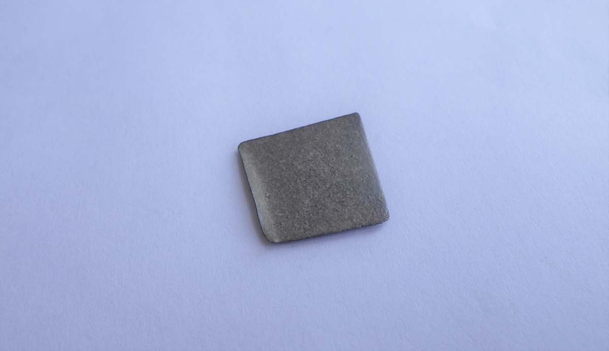 Tynn, jevn metallplate med en tilnærrmet kvadratisk utforming. Dette kan være et plateavklipp fra metallarbeid.