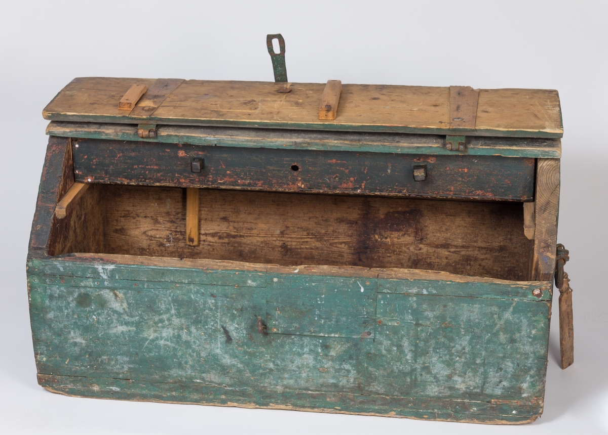 Solid vertøykiste i treverk med skrått lokk festet med to kraftige jernbeslag. I tillegg et jernbeslag til å feste et hengelås i front. En indre skuff delt i tre i øverste del av kista. I lokket er det gjort rom for ei sag og i indre front vegg feste til den ene øksa. Et kraftig jernhåndtak i hver side. I det ene håndtaket er det festet en tre-etikett med navnet  til eieren påført med blyant.