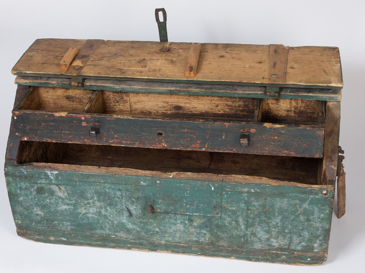 Solid vertøykiste i treverk med skrått lokk festet med to kraftige jernbeslag. I tillegg et jernbeslag til å feste et hengelås i front. En indre skuff delt i tre i øverste del av kista. I lokket er det gjort rom for ei sag og i indre front vegg feste til den ene øksa. Et kraftig jernhåndtak i hver side. I det ene håndtaket er det festet en tre-etikett med navnet  til eieren påført med blyant.