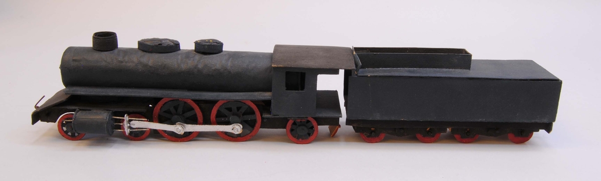 Leksaksånglok (:7) med tender (:8) av huvudmaterialet papp. Delarna är limmade eller sammanfogade med rött lack. Loket har fem hjulpar. Två av dem är av större diameter och kopplade via silvermålade koppelstänger. Hjulen är gjorda av papp och hjulaxlarna av runda träpinnar. Loket är målat i svart och hjulringarna i rött.
I lokets främre ände och i tenderns (:7) bakre ände finns koppel av ståltråd. Loket och tendern har varit sammanfogade med ett snöre men lacket som höll det på plats har lossnat från tendern och hänger från ångloket.