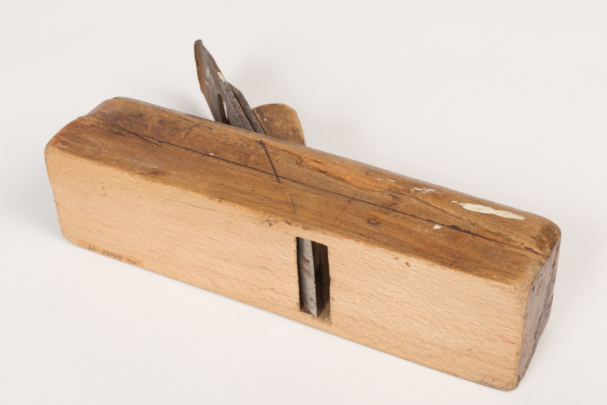 Høvel med tilnærmet kvadratisk tverrsnitt og plan såle. Har høveljern, klaff og kile. Stokkens oversider har utsparinger. Kilen er dekorert med et liljemønster (blyanat?) og har tynne dekorlinjer langs stokkens overflate og en midt på hver sideflate. Sporene etter slag på stokkens bakre kortside - i forbindelse med at høveltangen (jernet) skulle stilles/reguleres. 
Spor etter råte i et mindre felt på høyre langside.
Sålen er av bøk og øverste del av stokken er i bjørk.