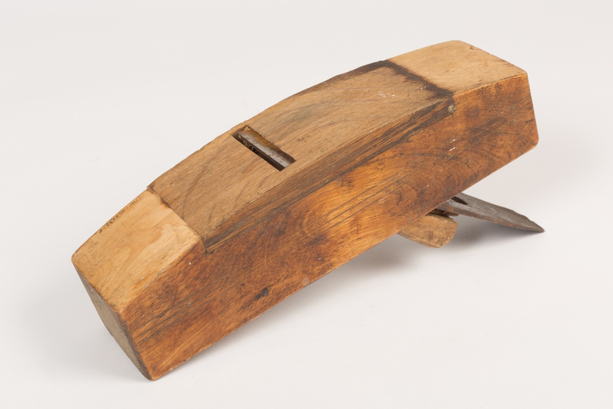 Buehøvel med høvelstål, klaff (sponbryter) og kile. Høvelstokken har buet såle og tre paralelle dekorstreker risset inn langs begge sidene. Et lengre felt av sålen er innfelt med et stykke hardere treverk (eik/nøttetre?). Oljet.