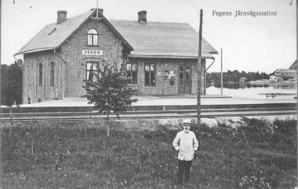 Vykort, "Fegens järnvägsstation".  Stationshuset uppfördes av Varberg-Ätrans Järnvägs AB och invigdes 1911 och ersatte det äldre. Stationen ligger vid sjön Fegen som skymtar till höger. I förgrunden står en man i ljus uniform.
Vykortsförlag: Svenska Litografiska AB Stockholm.