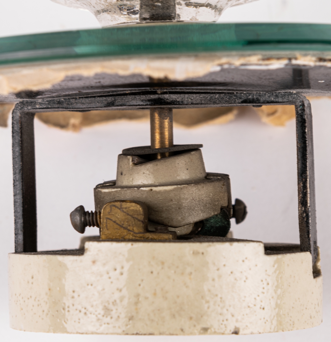 Strömbrytare, glas, plåt,stål, porslin mm. Runt tapetskydd av glas. Strömbrytarknappen av 12-kantigt glas. Etikett på porslinsdelen " 608 88 n"
Papperstapetrester kvar i beige, brunt, vitt, gulbrunt, rött oc hgult. Har suttit på väggen i vindskammaren i Blewegården, Kv. Resedan1, Gävle.