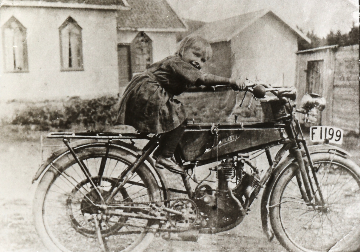 En Wanderer med reimtrekk modell 1907 med Hjørdis Møllebakken, f.1917,  på setet. Ved Elim, Metodistkirken i Hvittingfoss.