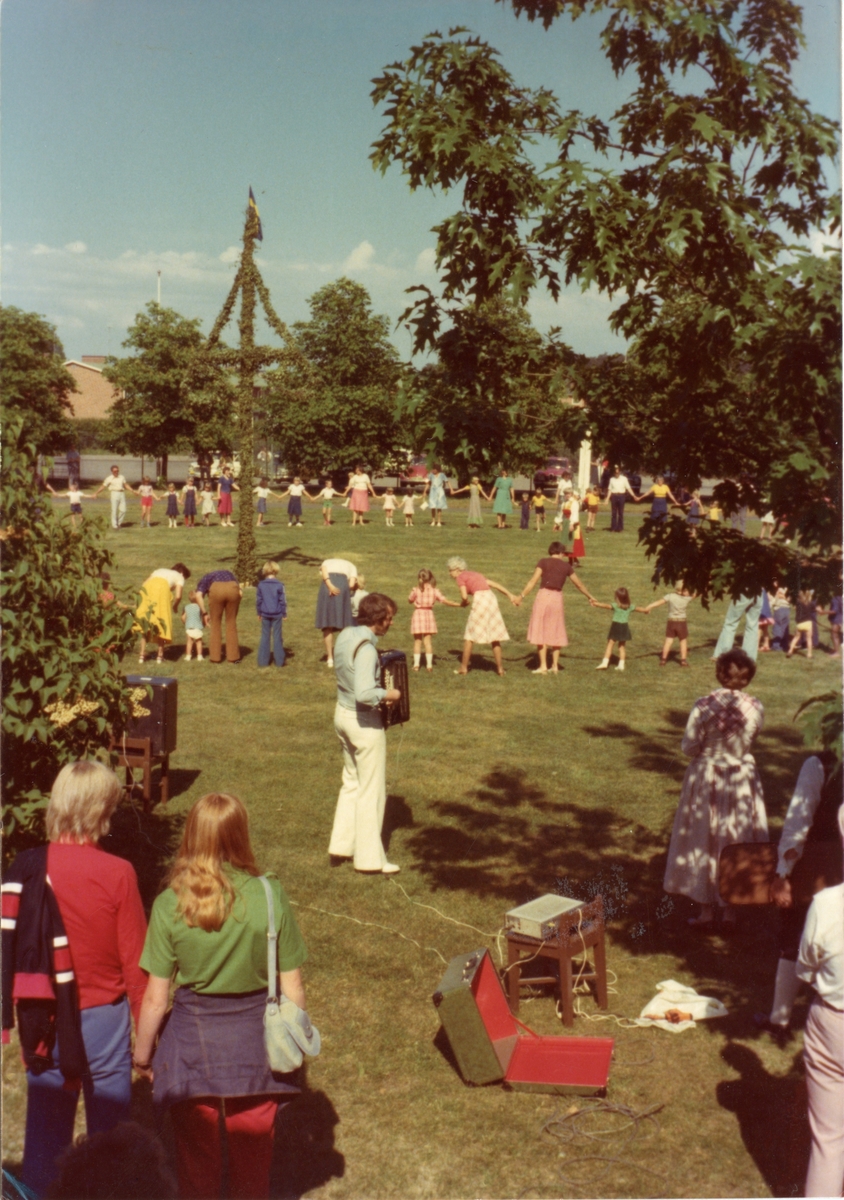 Bild från Folkets Park i Linköping. Midsommarfirande, dans runt en midsommarstång. I förgrunden en man med ett dragspel.