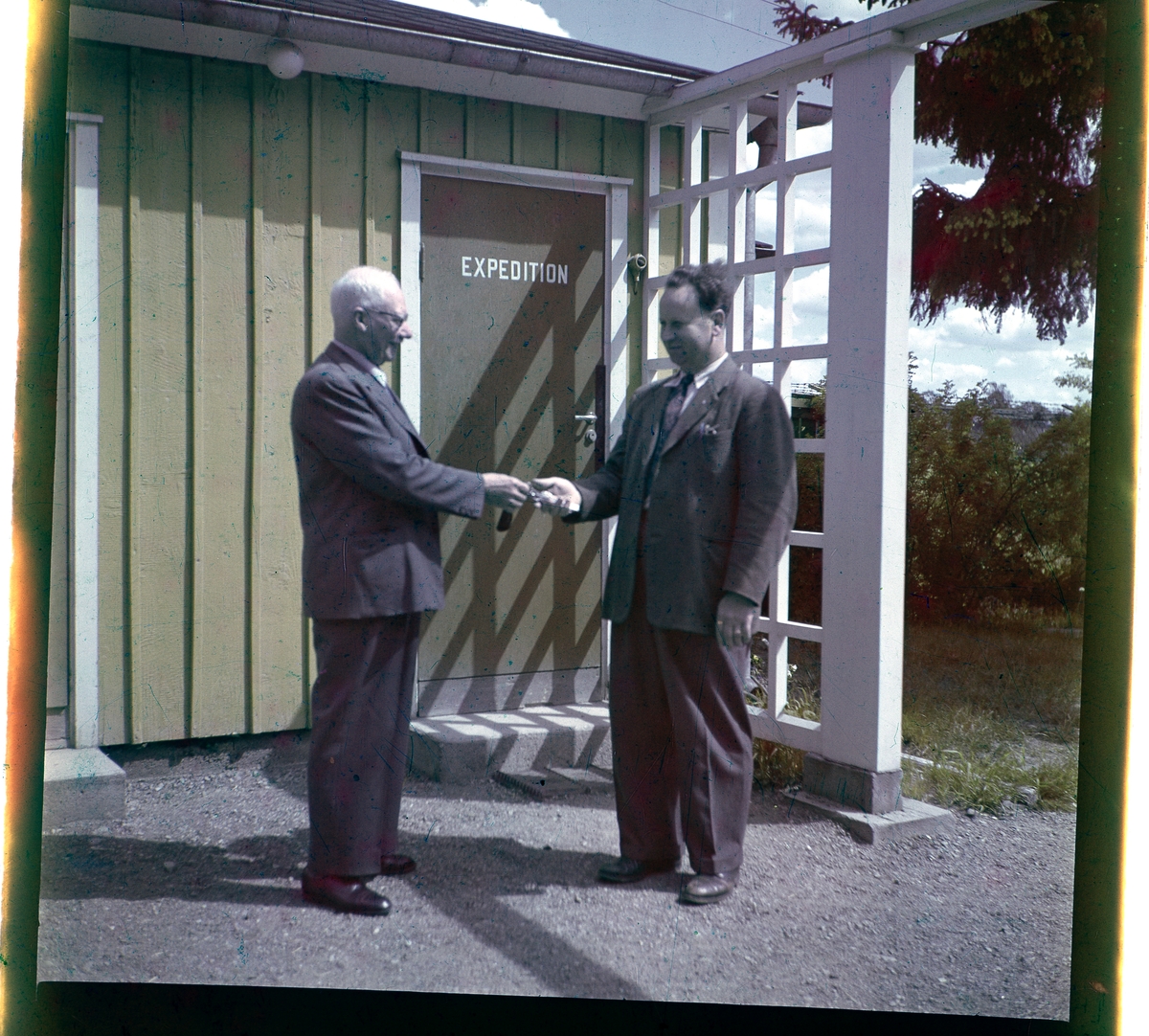 Negativ på två män utanför en byggnad i Folkets Park i Linköping. Personerna är Herman E. Nilsson och Alvar Vincent.