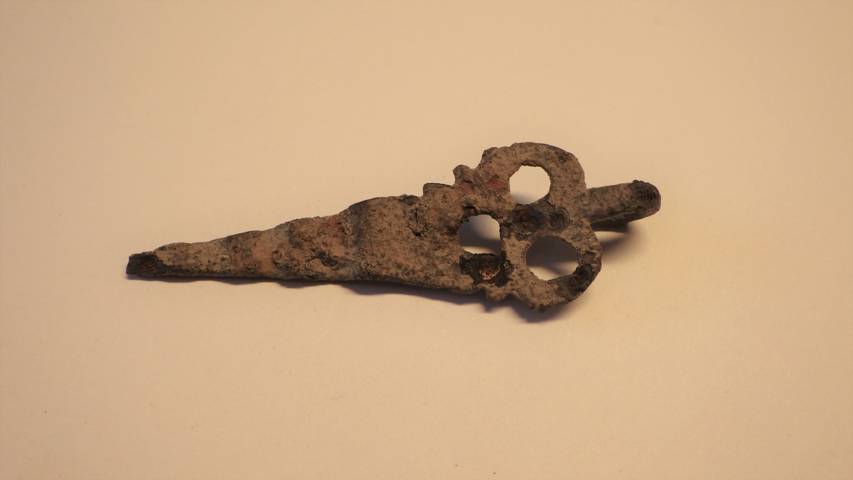 MALV: L. 7, 0 CM, ST. B. 2, 2 CM, TREKANTET, LANGSTRAKT FORM M. TRE HULL I DEN BREDESTEENDEN. DEN SMALESTE ENDEN ER BØYD I BØLGER. I DEN BREDESTE ENDEN ERDET ET ØRE TIL OPPHENGING. 