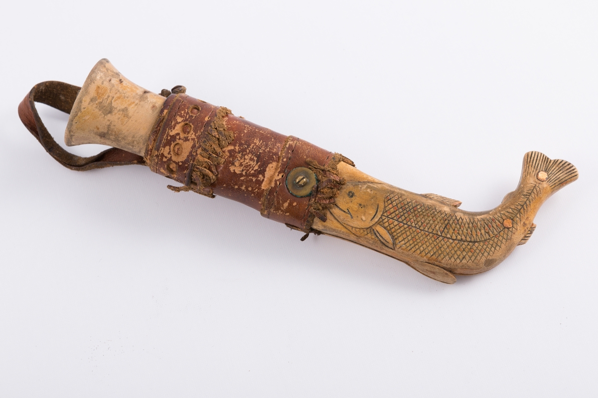 Tollekniv med slire og beltehempe i lær. Skaft tilvirket av lakkert treverk mens slire av lær og treverk. Nederste delen av sliren formet som en fisk.