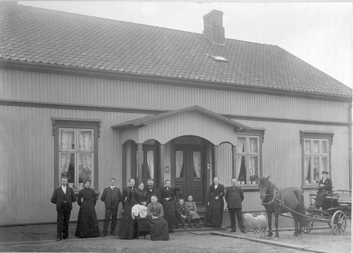 Gruppebilde utenfor Knud Mørchs gård i Sandesund, Sarpsborg. Knud Mørch f. 1840 var skipsekspeditør og hadde bolig i Elvegata i Sarpsborg. 
I tillegg til Knud er  er disse antakelig med på bildet: kona Josefine f. 1857, sønnens Oslvald f. 1879 (kontorist på skipsmeglerkontor) og Einar f. 1884 (gårdsgutt) og datter Elvira f. 1880. Ole Ols. f. 1879 i Tune er kontorist i ekspedisjonen). Kilde folketelling for 1900 Sarpsborg kjøpstad.)