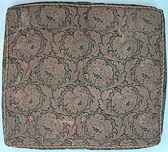 Fyrkantig sittdyna med kordongsnören runt och puskor.
Dynan är stoppad, och klädd med gul och blå epinglé med stora blommor.