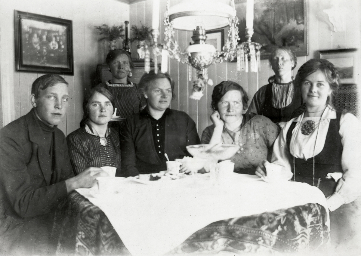 Kaffeselskap i oppstugo i Krossvegen.  F.v Johannes Saga f. 1897 d. 1981, Anne H. Saga f. 1894, Ronnaug H. Saga f. 1888 d. 1976, Dordi E. Nordbø f. 1882 d. 1966, Mari Saga f. 1882 d. 1973, Ingeborg Skogen f. 1872 d. 1958 og Bergit E. Nordbø (Bia) f. 1890 d. 1936.