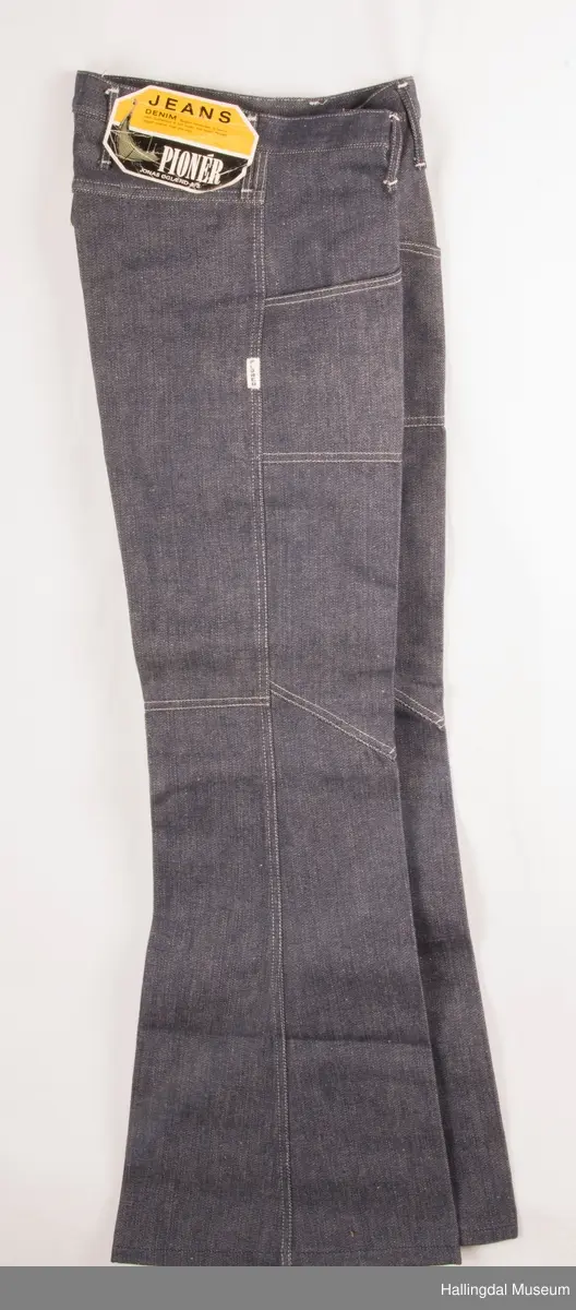 Mørk blå slengbukse i dongeri. Lavt liv.  Påsydde utvendige lommer foran og bak.  Metallglidelås i gylf.