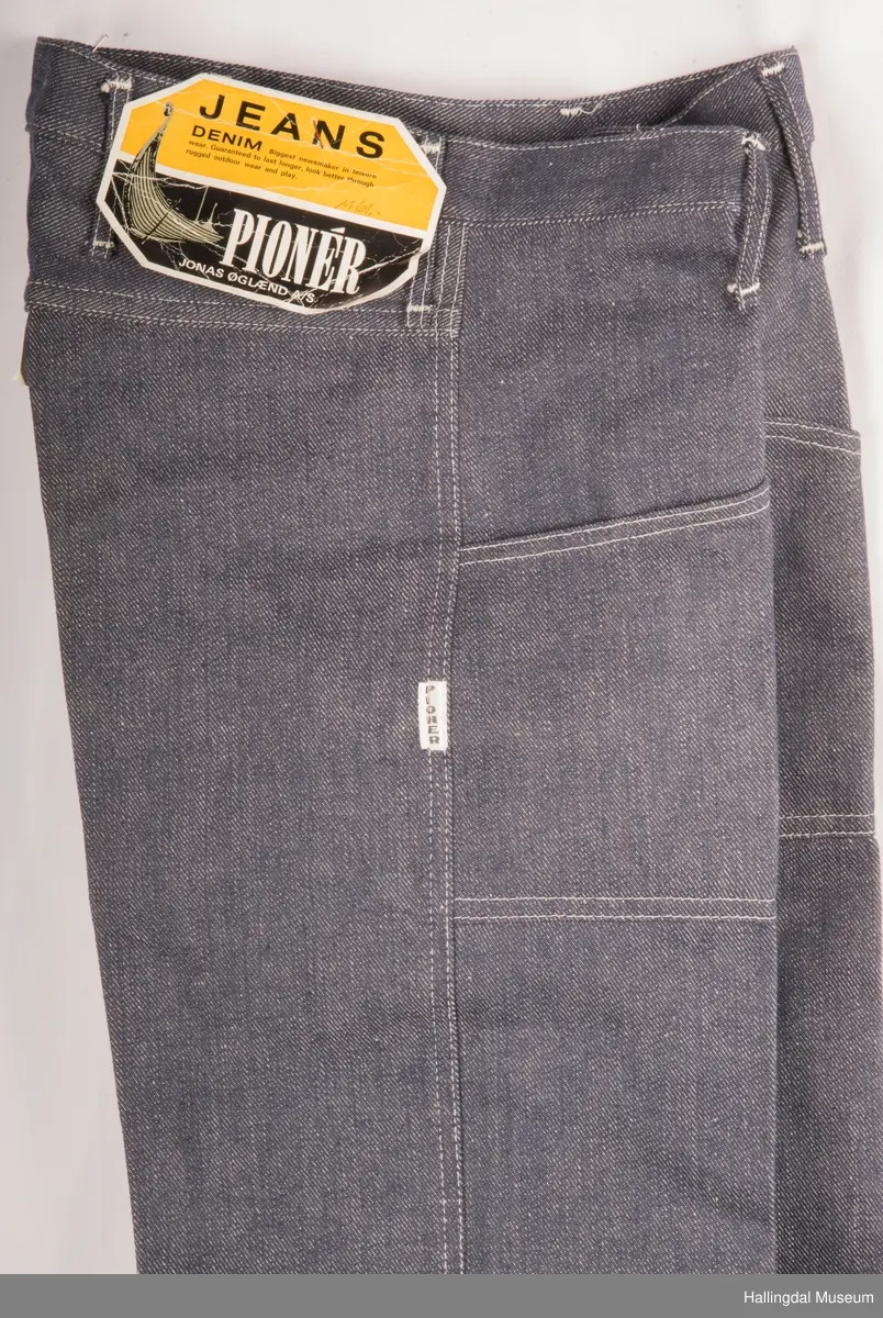 Mørk blå slengbukse i dongeri. Lavt liv.  Påsydde utvendige lommer foran og bak.  Metallglidelås i gylf.