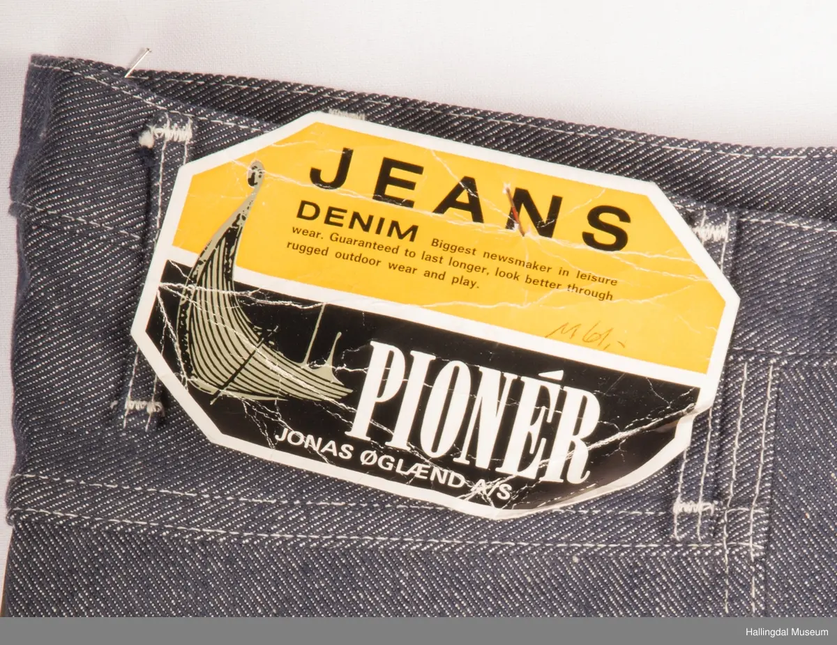 Mørk blå slengbukse i dongeri. Lavt liv.  Påsydde utvendige lommer foran og bak.  Metallglidelås i gylf.