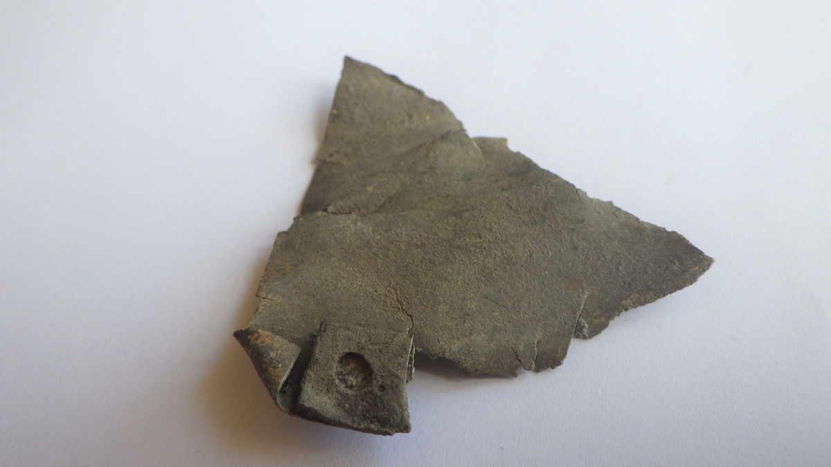 MALV: L. CA. 57 MM, TYNN PLATE, AVBRUKKET, MED TO SIDER I RETT VINKELPÅ HVERANDRE. PÅ DEN ENE SIDEN SITTER ET OMBØYET, KVADRATISK ØRE MEDHULL. 