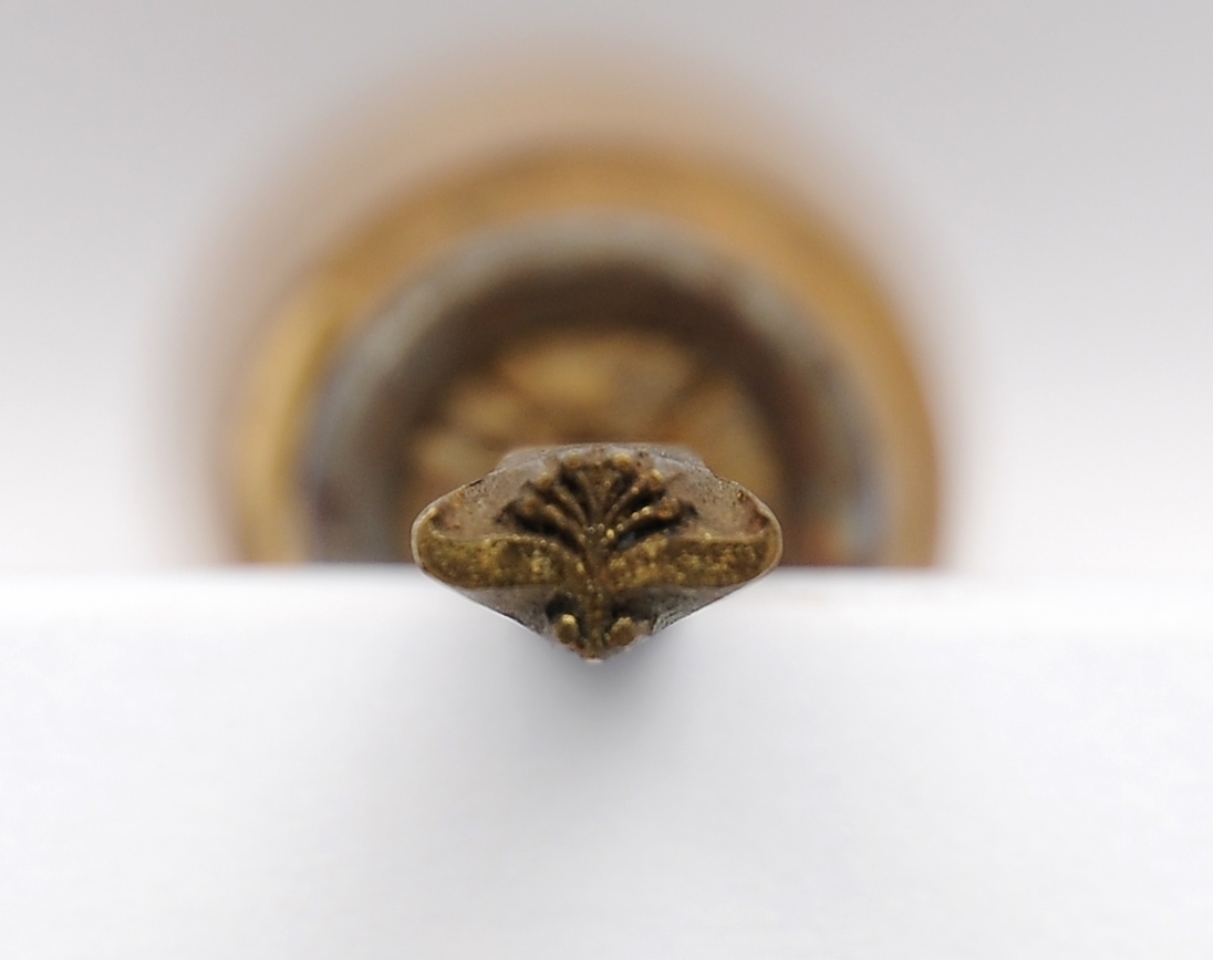 En liten kasse med en forgyllerpute og en skuff hvor det oppbevares ulike bokbindervertøy/forgyllerverktøy. Utstyret består av 5 ulike fileter/forgyllingsverktøy, 1 skiftekasse, 1 kniv, et stykker rødt kritt, 2 små ekser og flere ark med bladgull.
Dette er opprinnelig registrert som skomakerverktøy. Kan det ha blitt brukt til å prege skolær?