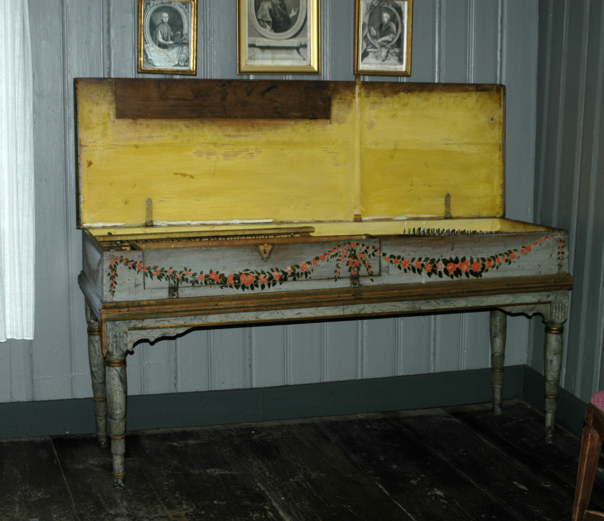 Taffelpiano , rettvinklet form. Kassa står ganske løst på 4 dreide bein. Malt utvendig på fronten med rankedekor i klassisk stil. Understellet er malt lys grått med grå-blå marmorering. Fra registrering:  "Spinett. Tre, jernhengsler, beinkledde tangenter." I protokoll anslått til å være fra 1790.