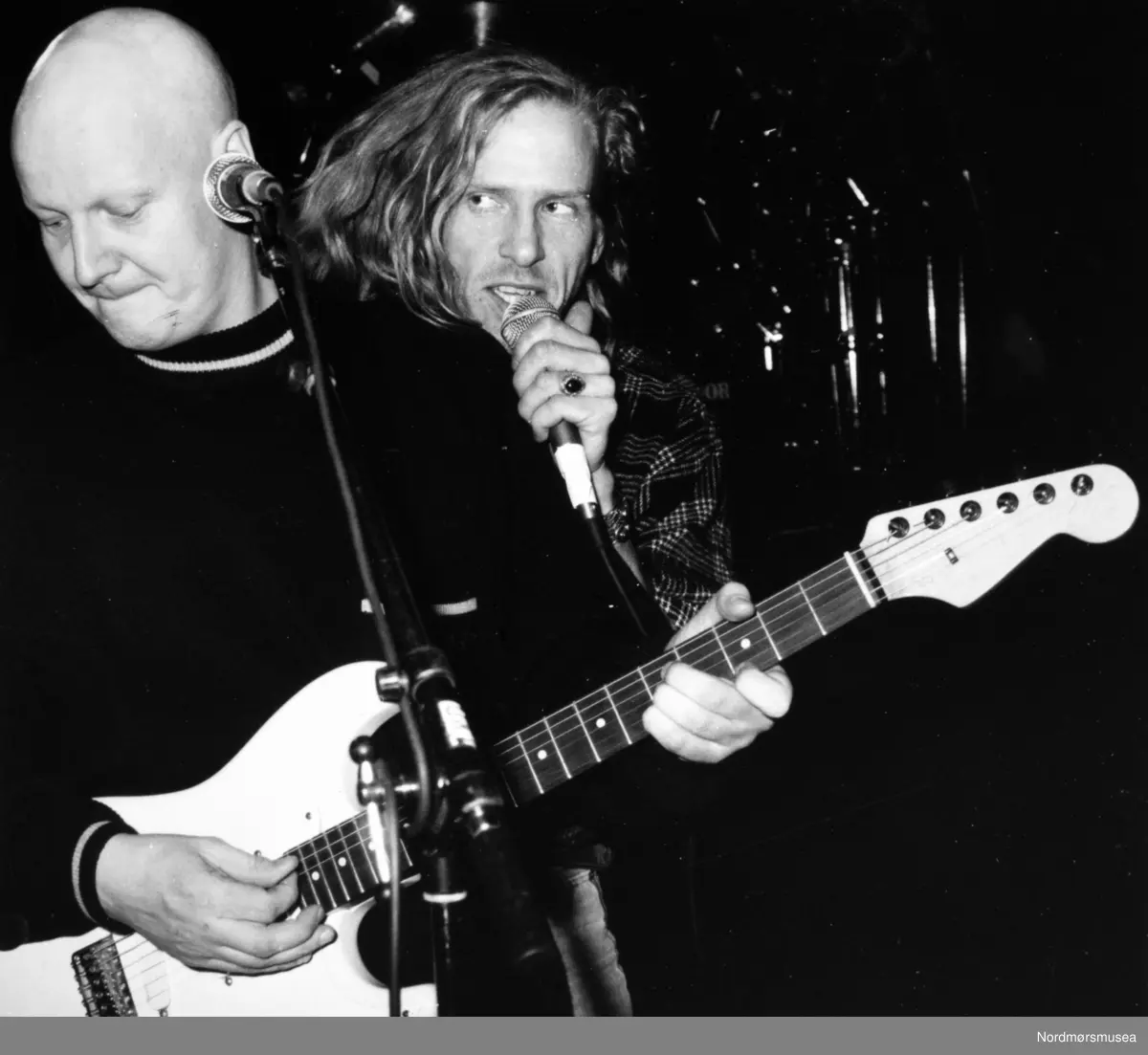 Øyvind Elgenes til høyre. 
Frode Alnæs (1959) er født og oppvokst i Kristiansund, der han bodde fram til han var ferdig med gymnaset i 1978. Frode visste tidlig i livet at han skulle bli musiker. Han hadde et talent, og han vurderte aldri noe annet yrke. (Det eneste måtte være skogvokter i Kristiansund, en herlig jobb i en by omtrent uten trær…). Fra han som 11-åring mistet håret og fikk sin første gitar av foreldrene, lukket Frode seg inne på gutterommet og øvde og øvde – aller helst til ”The Kinks” – yndlingsbandet!

1978-79 var han elev ved musikklinja på Nordmøre Folkehøgskole i Surnadal. Dette året kom til å bety mye for Frode, både som menneske og musiker. Han har siden hatt som motto: ”Alle burde få lov til å oppleve et år på folkehøyskole, også blåruss”. Allerede mens han gikk på folkehøyskolen komponerte han det meste av rockeoperaen «Frosken som ikke forsto et kvekk», som ble satt opp i Kristiansund sommeren 1979.

I 1979 ble Frode tatt opp i det aller første kullet på det nye jazz-studiet ved Trøndelag Musikkonservatorium, og i 1982 gikk han ut med karakteren 1 blank i gitarspill – det vil si best mulige karakter. På konservatoriet ble Frode kjent med musikere som Bjørn Klakegg, Tore Brunborg, Nils Petter Molvær, The Brazz Brothers og Ernst Wiggo Sandbakk.

Siden han gikk ut fra jazzlinja i Trondheim, har Frode livnært seg som profesjonell musiker og artist. I 1982 flyttet han til Oslo, hvor han raskt opplevde stor suksess som freelance-musiker i studio, på scener og turneer sammen med mange av de største navnene i norsk jazz- og pop/rock-verden.

I denne perioden etablerte han seg i toppsjiktet, og det begynte å ryktes at et nytt ”gitar-geni” (med parykk) hadde nådd norske scener og platestudioer. Frode var først og fremst jazzgitarist, men ble raskt kjent som en musiker som beveget seg i flere sjangre. Dette ble – og er – hans varemerke. Frode har alltid vært en improviserende musiker, som ikke ønsker å havne i en musikalsk bås. Han vil være fri som fuglen!

”Dance With A Stranger” skulle bli Frodes virkelig store gjennombrudd som låtskriver, gitarist, artist og entertainer. Bandet ble startet i 1984 av Frode og kompis, bodøværing og trommis Bjørn Jenssen (som da spilte i blant annet Jon Eberson Group) og senere fikk de med seg den særpregete vokalisten Øyvind ”Elg” Elgenes fra Kristiansund og bassist Yngve Moe fra Tromsø.

Dance With A Stranger opplevde det store gjennombruddet etter en opptreden etter Spellemannsprisen i 1988. Det var også da, rett før de gikk på scenen, Frode hadde bestemt seg for å kaste parykken. Det ble for godt. En befriende kveld på flere måter med andre ord, og et nytt liv i norsk musikkverden ventet Frode og ”Dance With A Stranger”. Kort fortalt ble bandet en av norsk pop/rockmusikks store suksesser. De har gitt ut åtte album og vunnet flere spellemannspriser.

Etter mange år i Oslo flyttet Frode et par år tilbake til Trondheim, og deretter til hjembyen Kristiansund. Sammen med en entusiastisk dugnadsgjeng bygde han opp og restaurerte en verneverdig bydel på Innlandet, øya han trådte sine barnesko. Et arbeid som ble prisbelønt blant annet av Fortidsminneforeningen i 2002. Han drev i mange år Dødeladen Café og Kultursted, Tollboden og Tahitibrygga. Frode Alnæs er også grunnlegger av den årlige Tahiti-festivalen i Kristiansund.

Vinteren 2009 flyttet Frode tilbake til Oslo hvor han bor i dag. Han er en svært travel musiker, med mange reisedøgn i løpet av året. Aller helst går reisene til hytta på Kanestrøm på Nordmøre. Her har han skrevet mye av musikken sin, og her finner han ro og vandrer lange turer i fjell og mark.

I løpet av sin over 35 år lange karriere som profesjonell musiker, har Frode gjort nær 6000 konserter i Norge og Europa med ”Dance With A Stranger”, med andre band og artister og som soloartist. Han har spilt på de fleste store jazz- og rockefestivaler i Norge, og har turnert i mange år for Rikskonsertene. Han siste store engasjement her, i samarbeid med Riksteateret, var i ”Let it Rock” – en uhøytidelig reise gjennom rockens historie. Turneen gikk høsten 2009/vinteren 2010 og samlet fulle hus på nærmere 60 kulturhusscener over hele landet. Frode var både medvirkende og musikalsk ansvarlig for forestillingen.

Frode Alnæs har i alle år markert seg som låtskriver og komponist. I tillegg til å ha skrevet alle låtene til ”Dance With A Stranger”, har han skrevet musikk for en rekke andre artister, komponert flere bestillingsverk, blant annet operaen ”Donna Bacalao” (2008) og verket ”Kanestrøm” (2011). Høsten 2013 kom hans nye soloplate «Envy The Man» og vinteren 2016 fulgte hans første instrumentalplate i eget navn «Kanestrøm». Frode har de siste årene hatt en produktiv periode og skrevet mye ny musikk. I februar 2018 var han premiereklar med sin nye soloforestilling «Min dans med strenger». Forestillingen har høstet fantastiske kritikker og terningkast 6 landet rundt.Bildet er fra avisa Tidens Krav sitt arkiv i tidsrommet 1970-1994. Nå i Nordmøre museums fotosamling.