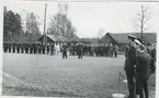 Långt dubbelled med civilklädda och militärer
en mikrofon på ställning mitt på plan